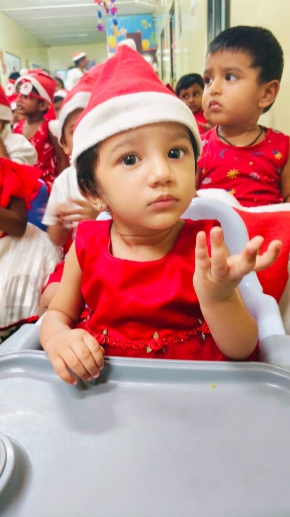 Toddler in festive Santa hat and red dress during a holiday celebration in Infant Care