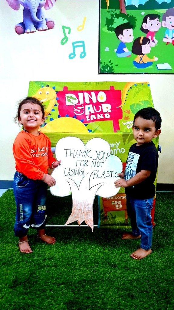 Toddlers with no-plastic awareness tree sign in Dinosaur Land play area